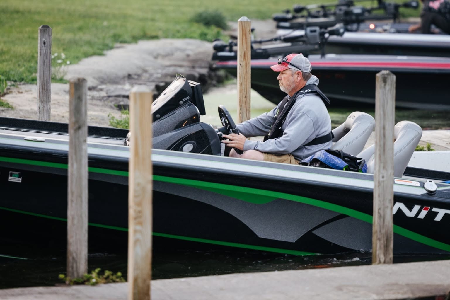 Angler steering a bass boat into the dock between wooden pilings