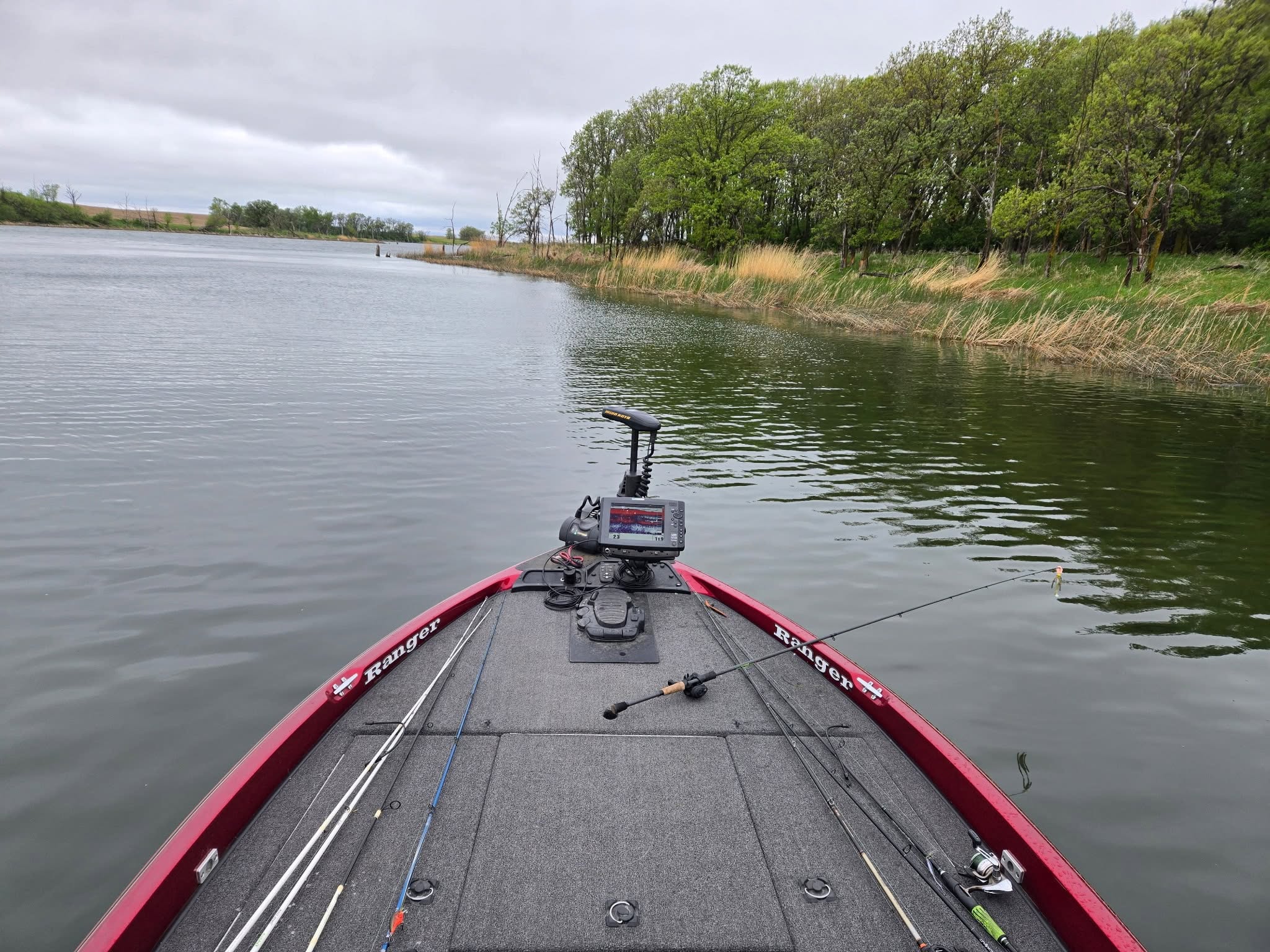 View from the bow of a bass boat down a quiet tree-lined channel