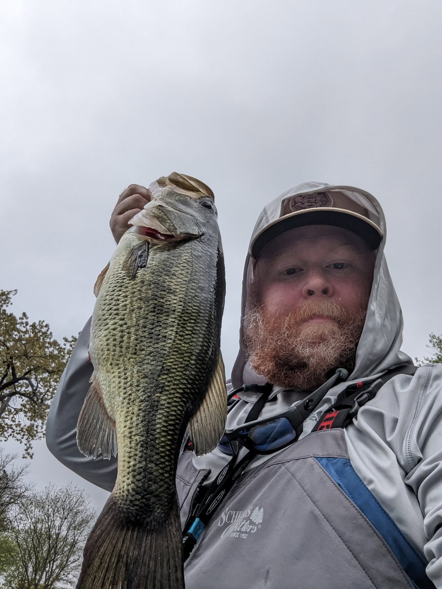 Angler holding a largemouth bass on an overcast day