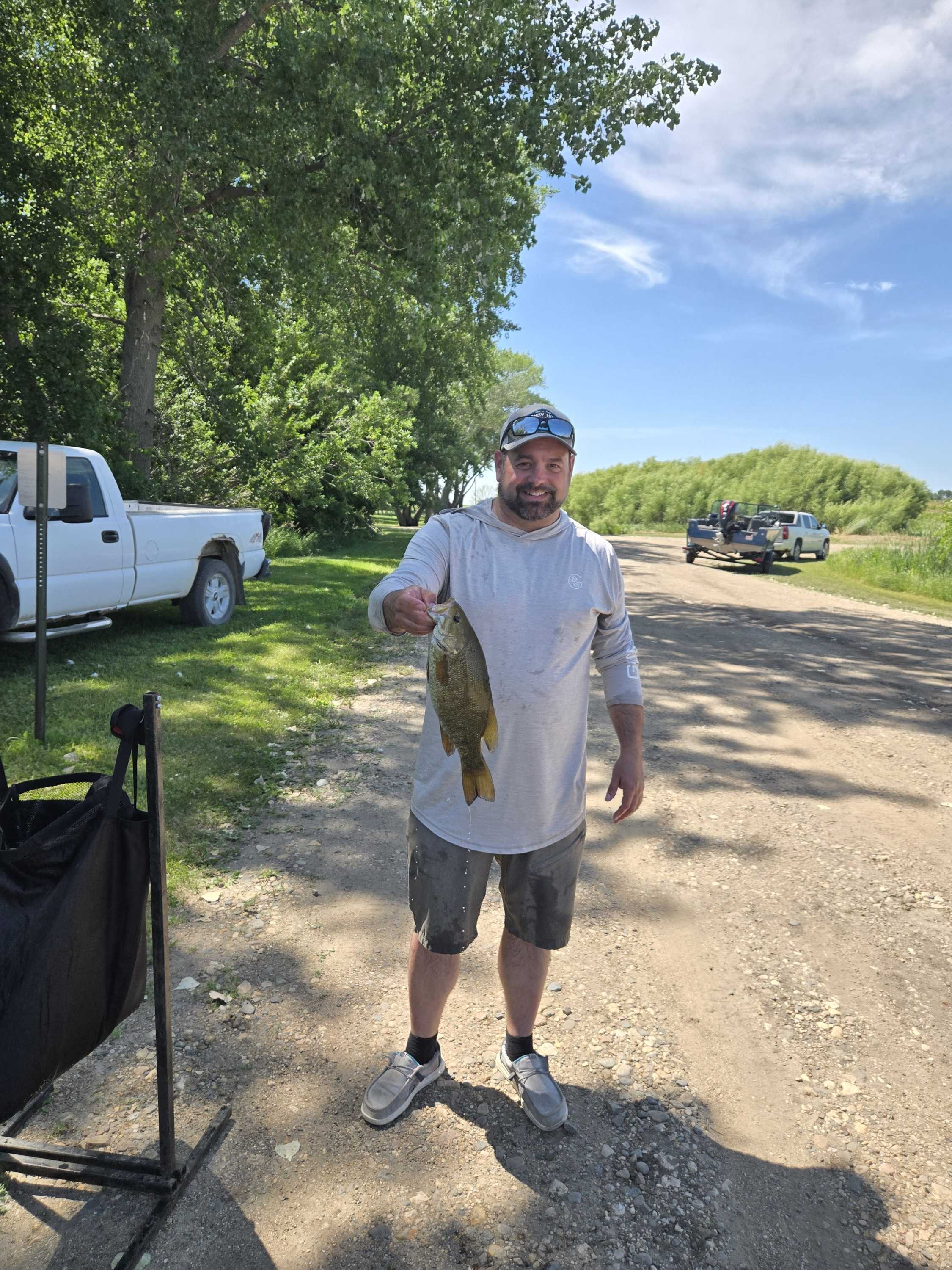Smiling angler holding up a smallmouth bass at the Blue Dog Lake ramp