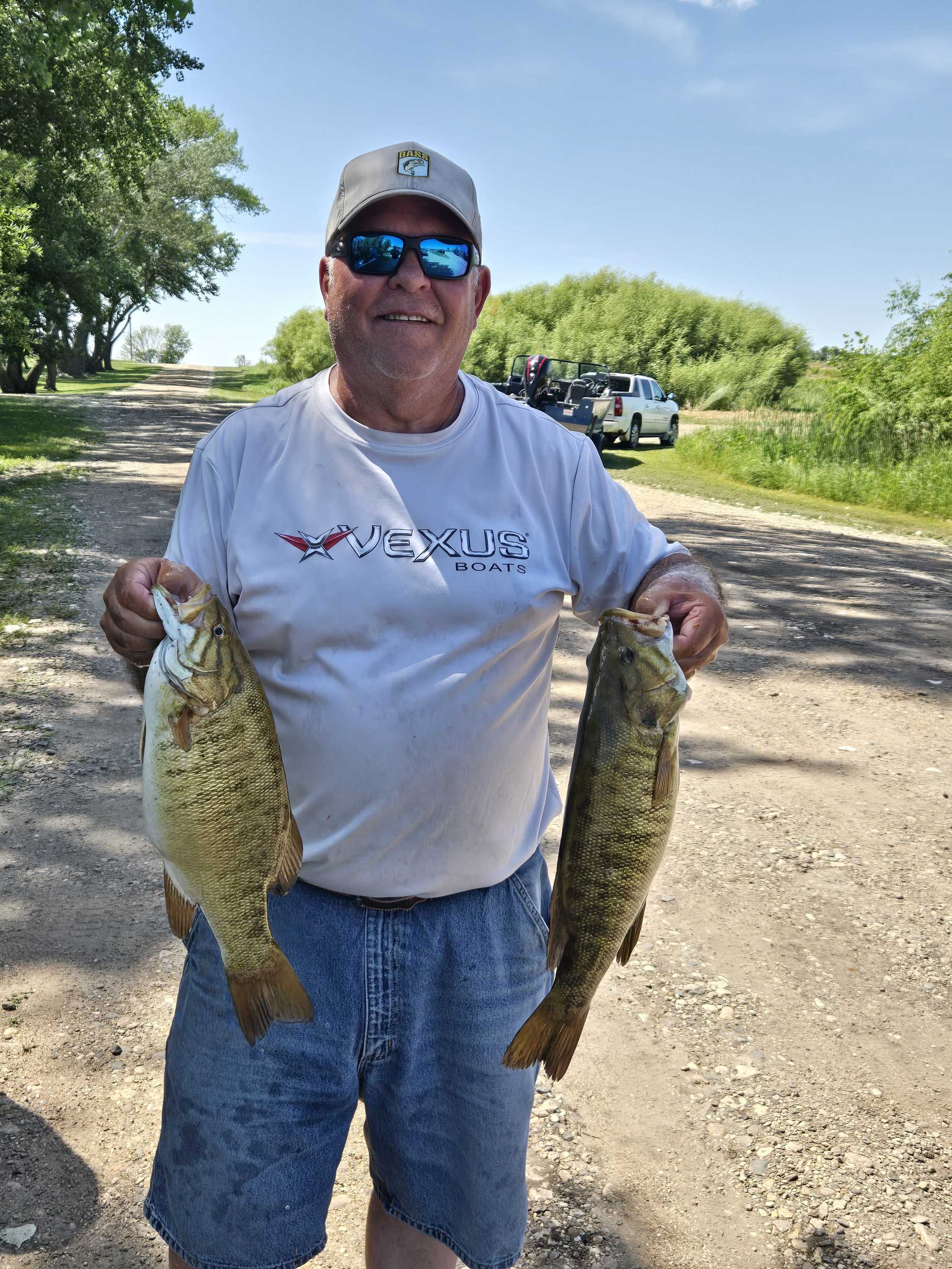 Angler holding two chunky smallmouth bass on the gravel road at Blue Dog Lake