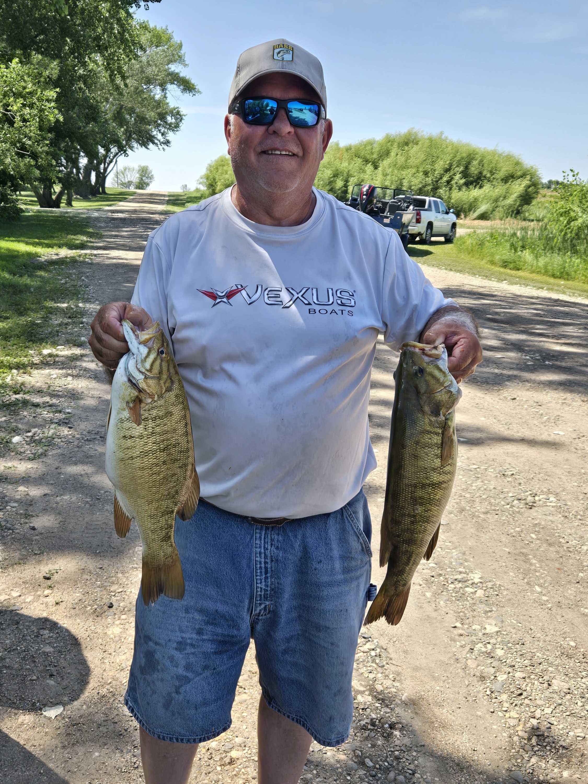 Angler holding up two smallmouth bass in the sunshine at Blue Dog Lake