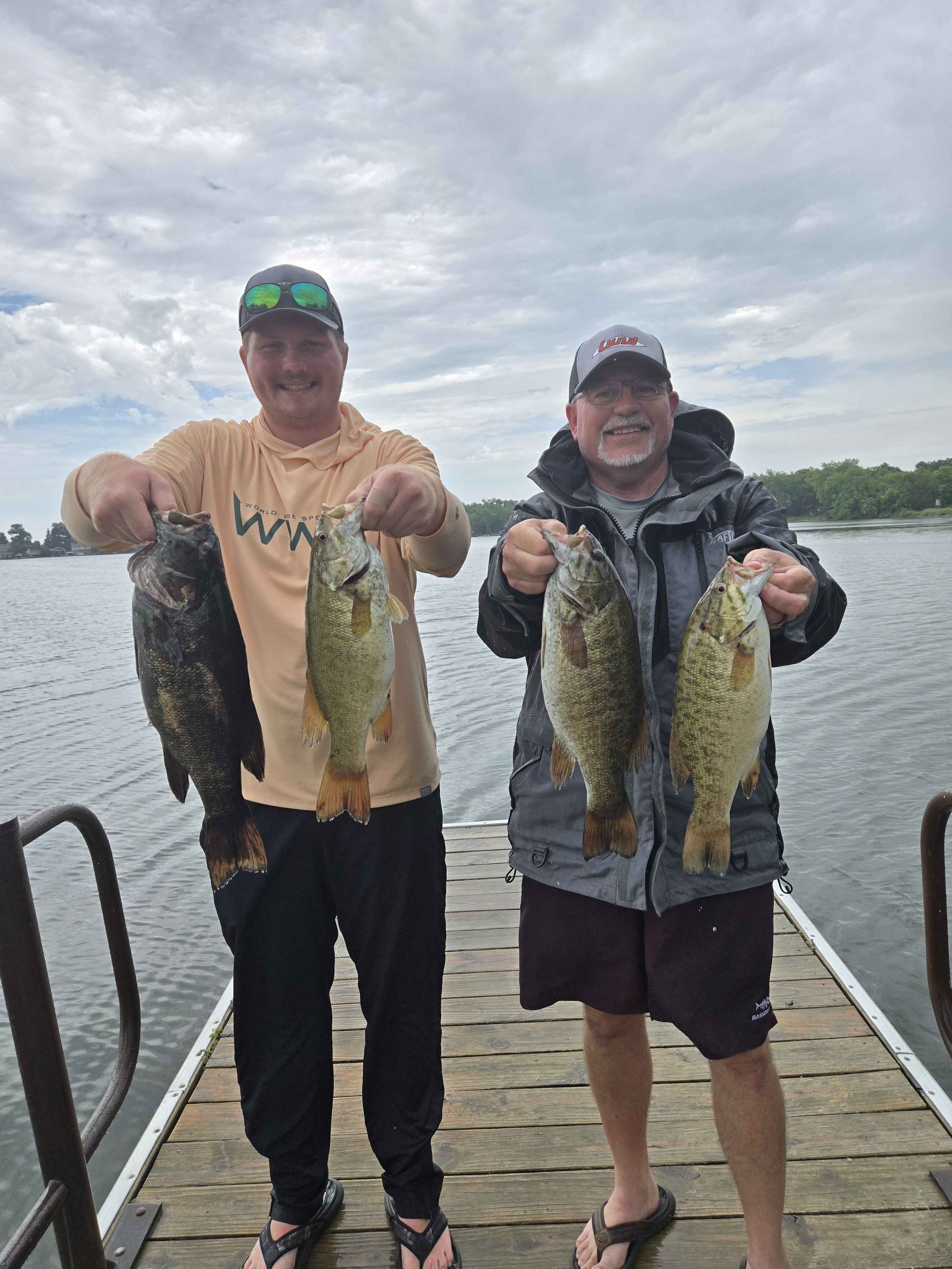 Two anglers holding four bass on the dock at Enemy Swim
